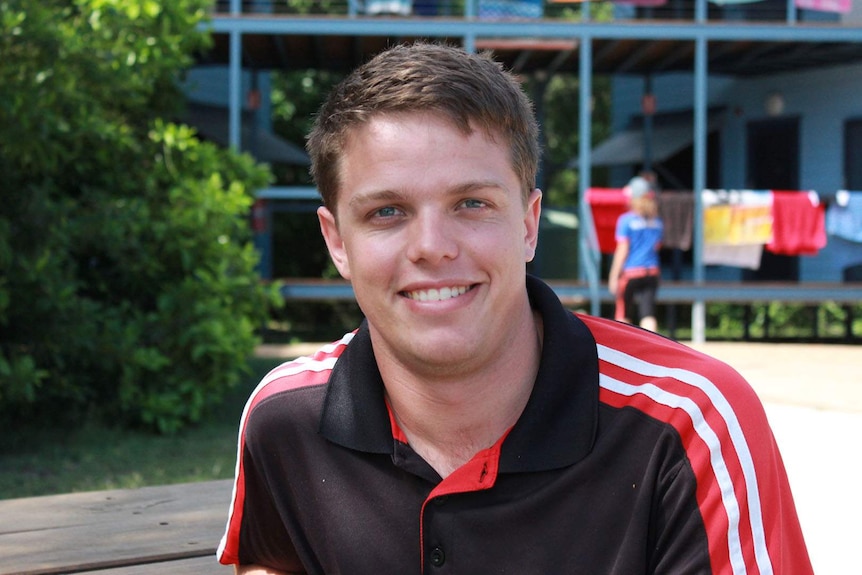 a young man sits on a park bench in front of a building