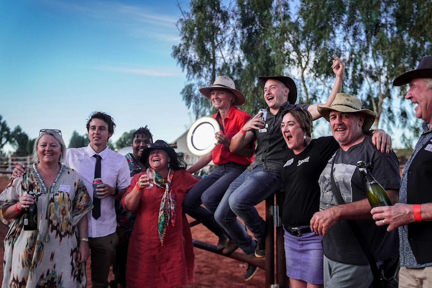 A group of people holding drinks cheer.