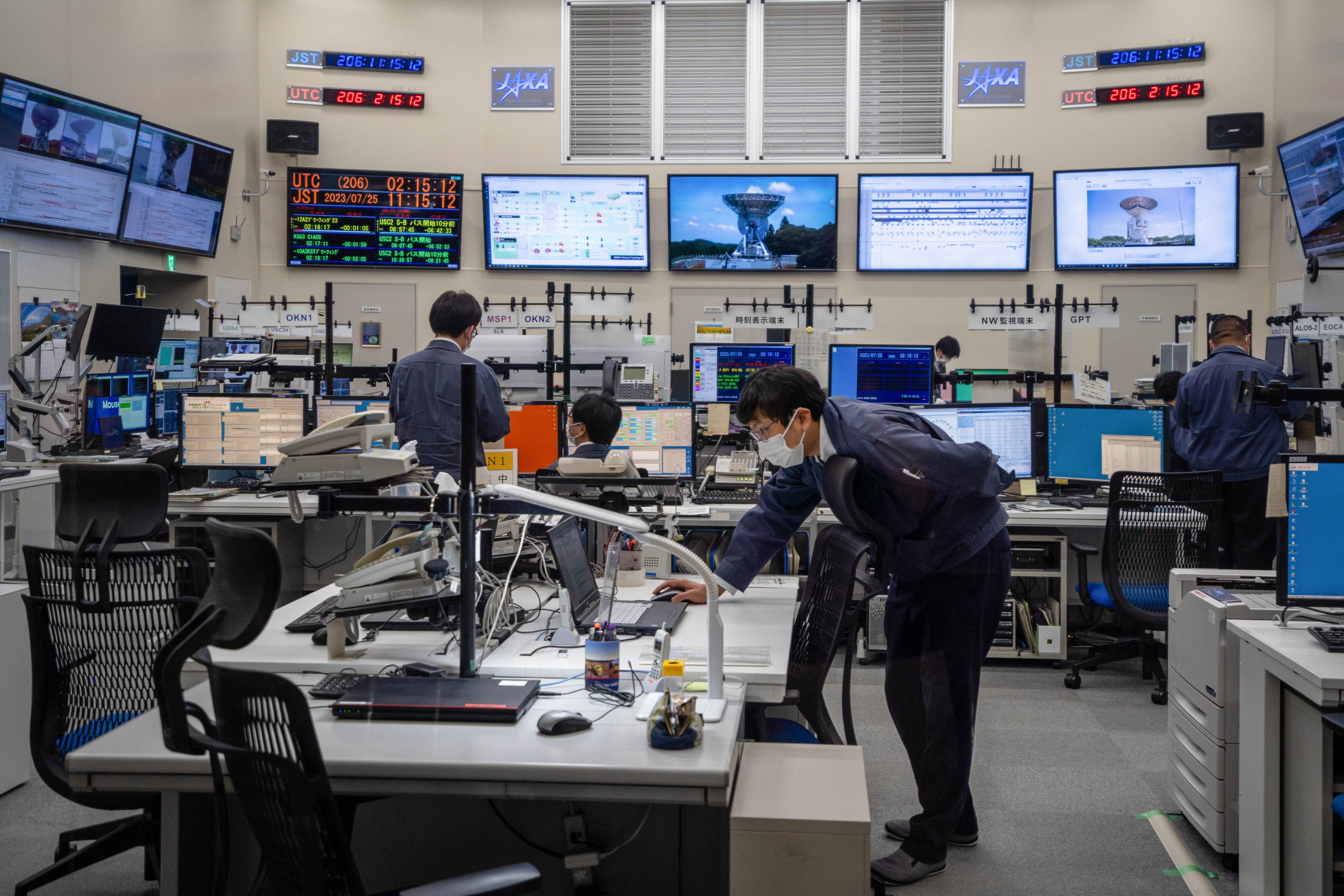 Men standing in a room with a lot of computers