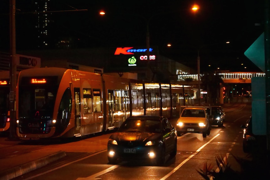 a tram at night next to cars