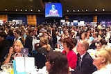 Mr Newman (seated at table) listens as ms Bligh speaks at the IWD breakfast in Brisbane.