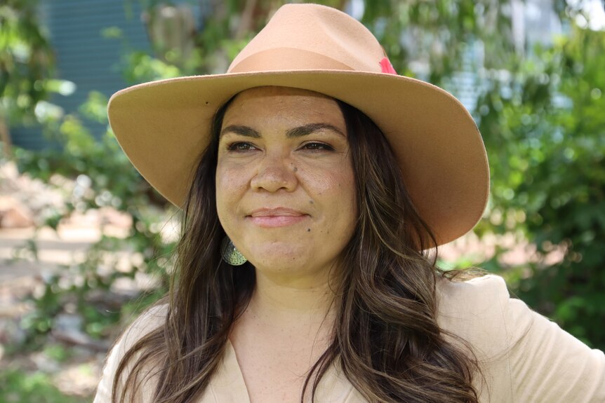 An Indigenous woman looks off into the distance while wearing an akubra.