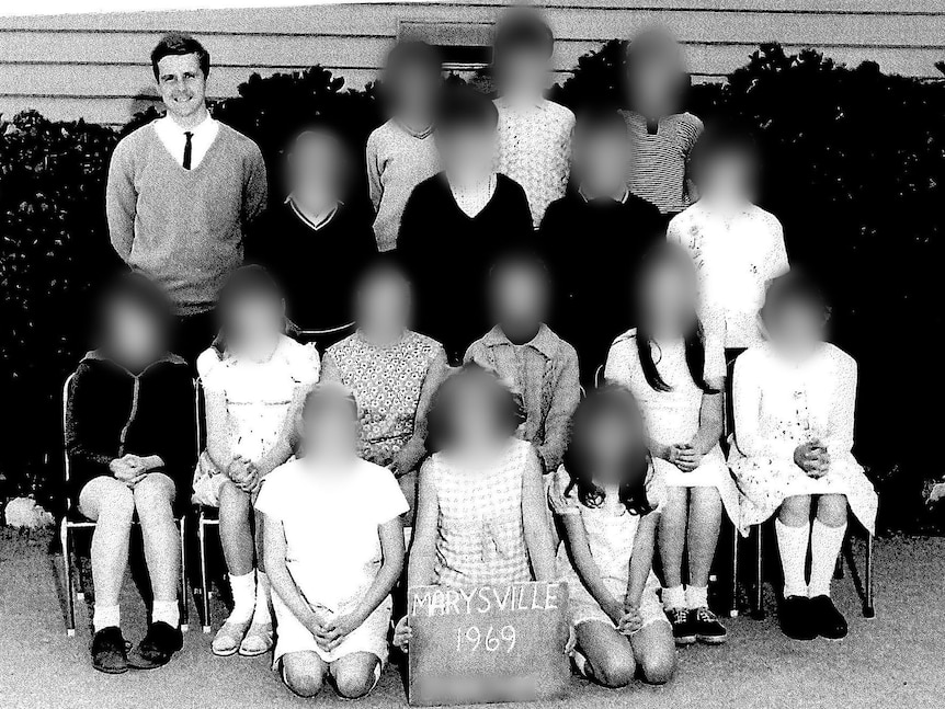 A black and white class photo with a male teacher and the faces of all the children blurred.