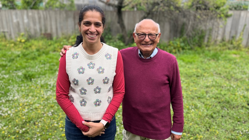 And Indian woman and Indian man smile at the camera in a grassy backyard.
