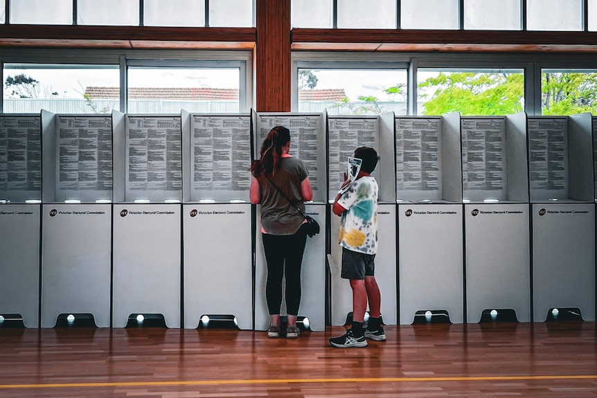 A woman and child stand at a polling station.