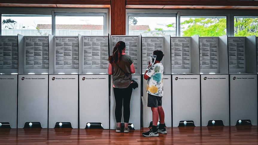 A woman and child stand at a polling station.