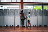 A woman and child stand at a polling station.