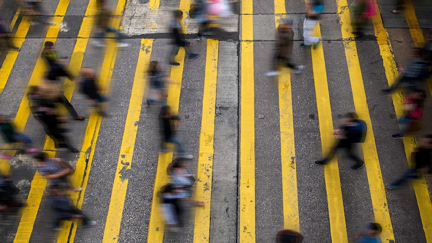 Blurred motion photo of people walking on city street, Hong Kong.