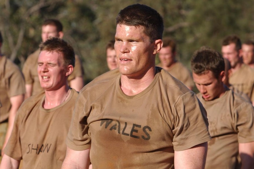 A man standing with a group of men wearing olive green shirts