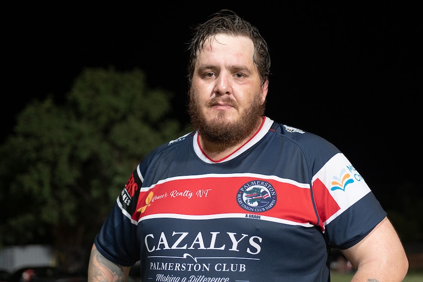 A man in a rugby jersey frowns at the camera