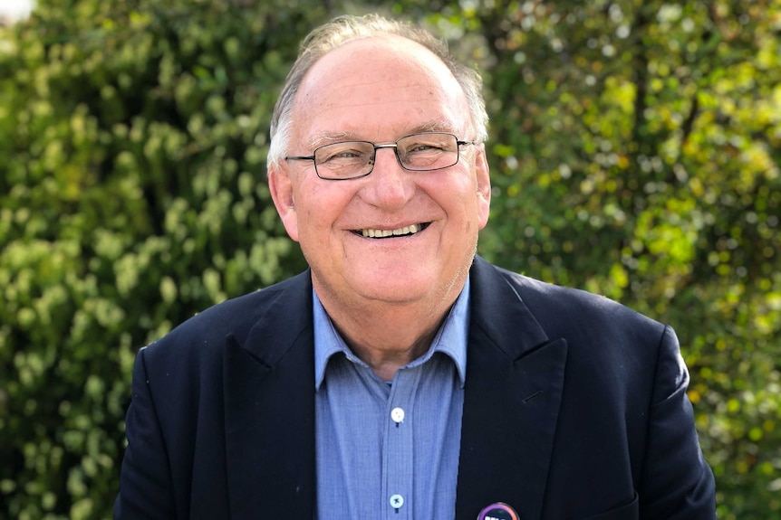 A man with glasses smiles at the camera.