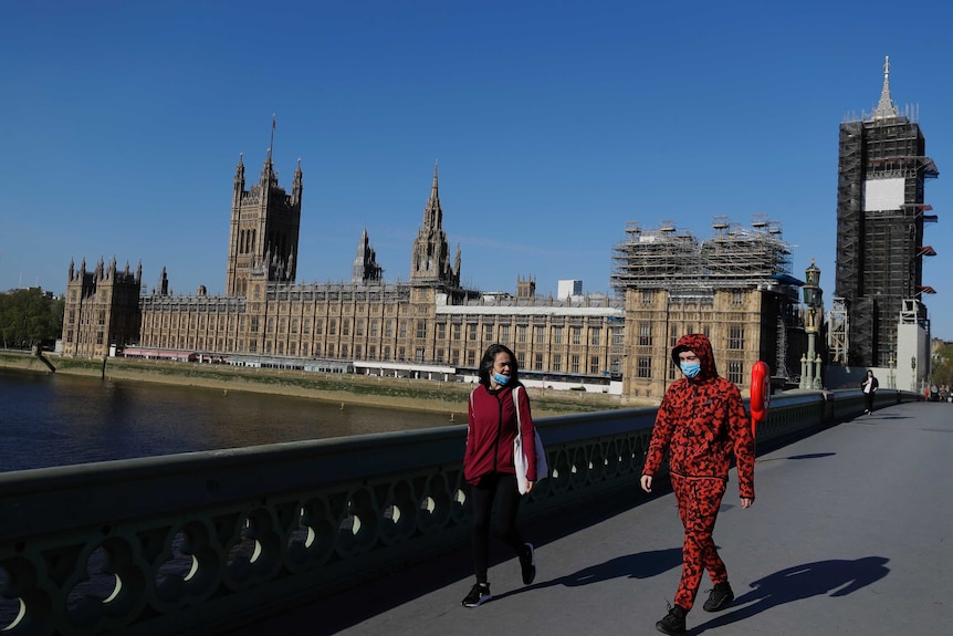 People wear masks as they walk near Britain's Houses of Parliament.