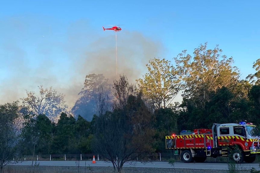 Helicopter flying over smoke with fire truck in right bottom corner