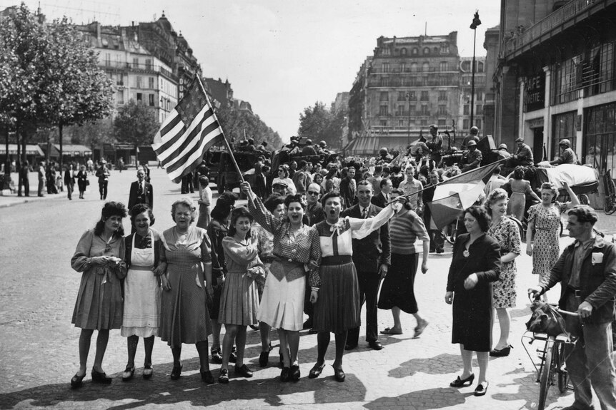 French civilians with American and French flags greet US and free French troops entering Paris.