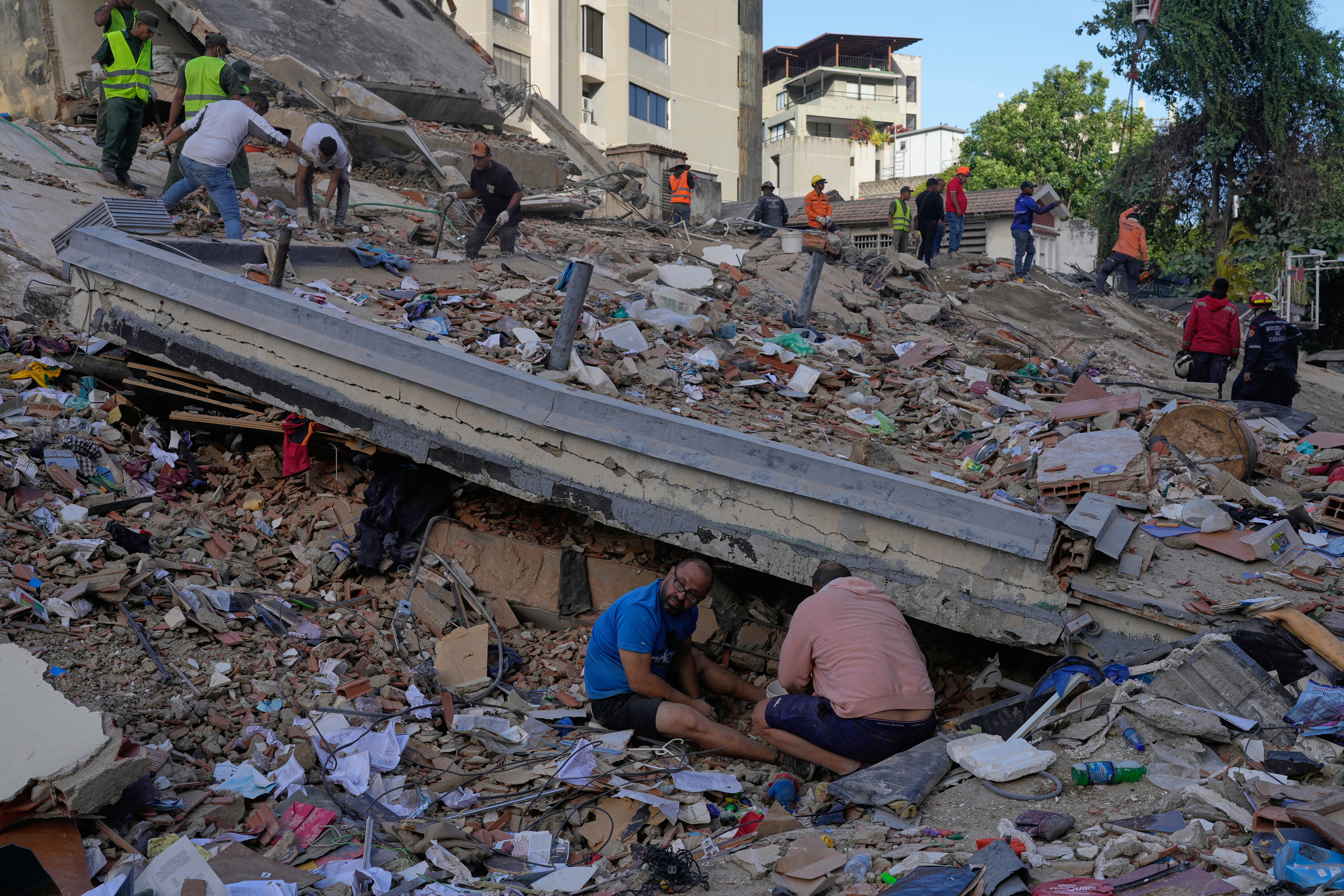people sit on rubble of a destroyed building