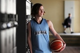 Teenager leaning against school lockers with a basketball
