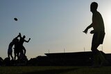A silhouette of a ruck contest in an Australian rules match.