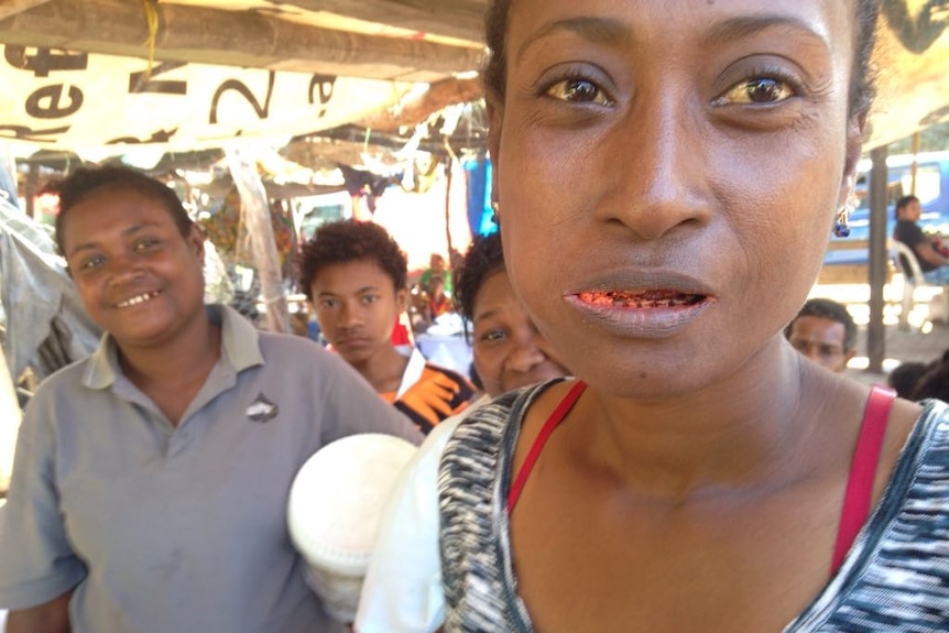 A close up shot of a woman chewing betel nut.