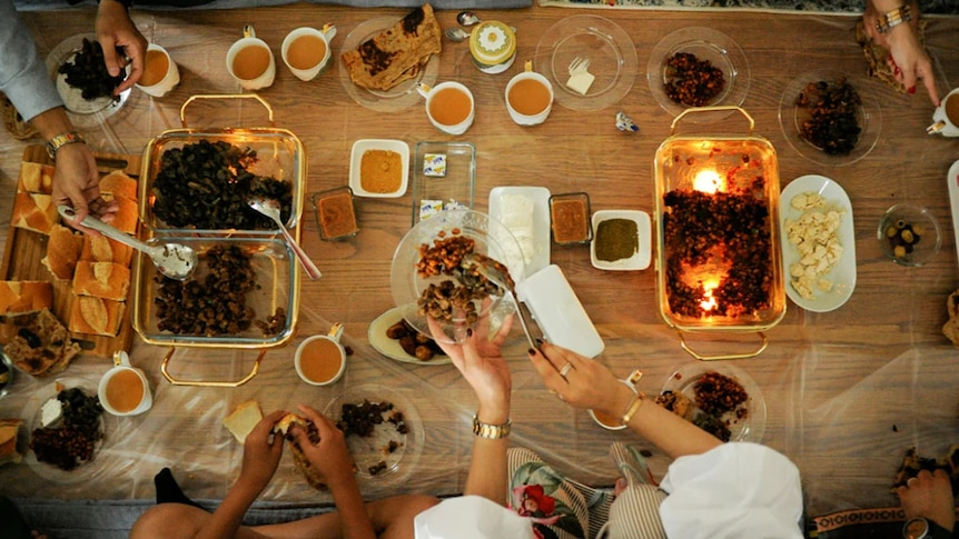 Food spread out on a wooden table as people serve their plates