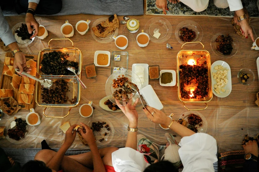 Food spread out on a wooden table as people serve their plates