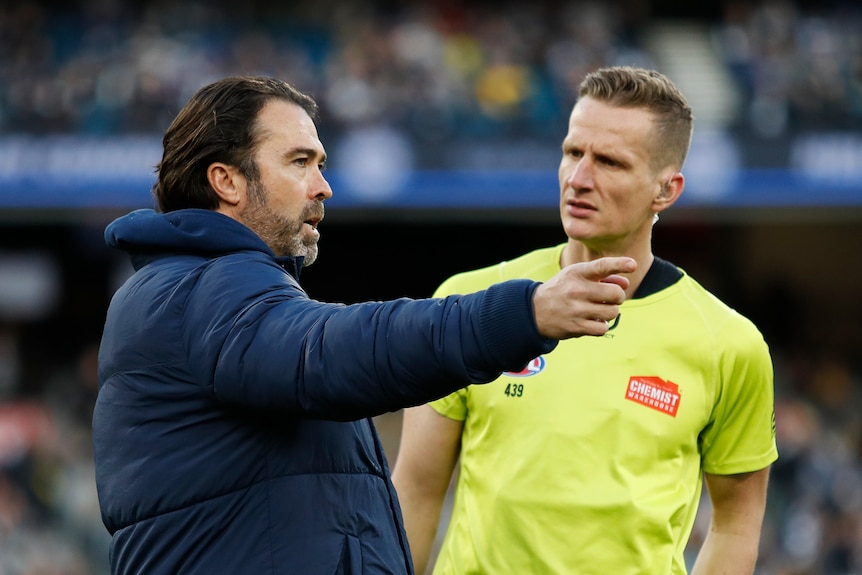 Chris Scott points as he talks to an AFL umpire