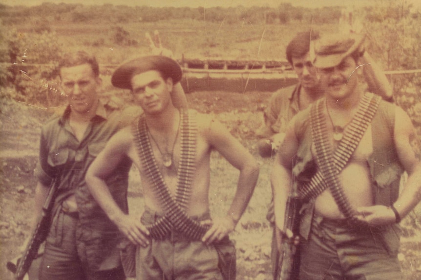 Four men in the Vietnam War, two wearing "bandolier" bullet belts across their chests.