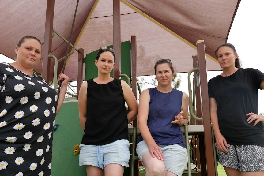 Four women stand in a row looking at the camera