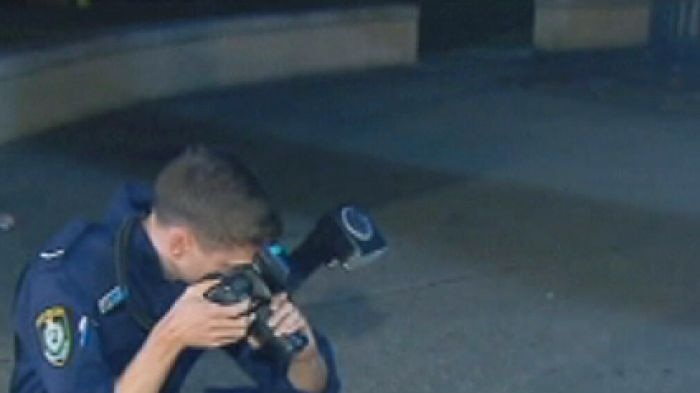 A police investigator photographs a beer bottle