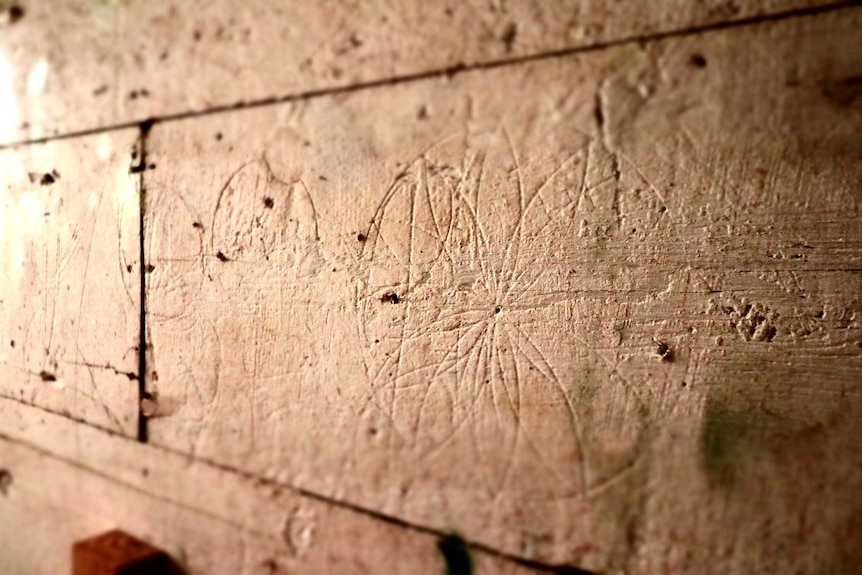 A circular hexafoil with several petals has been carved into a stone stable wall.
