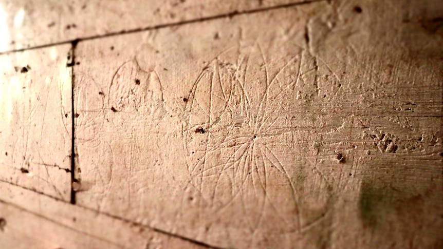 A circular hexafoil with several petals has been carved into a stone stable wall.