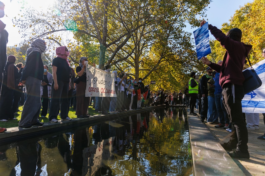 Pro-Palestinian protesters on one side of a body of water and pro-Isreal on the other. 