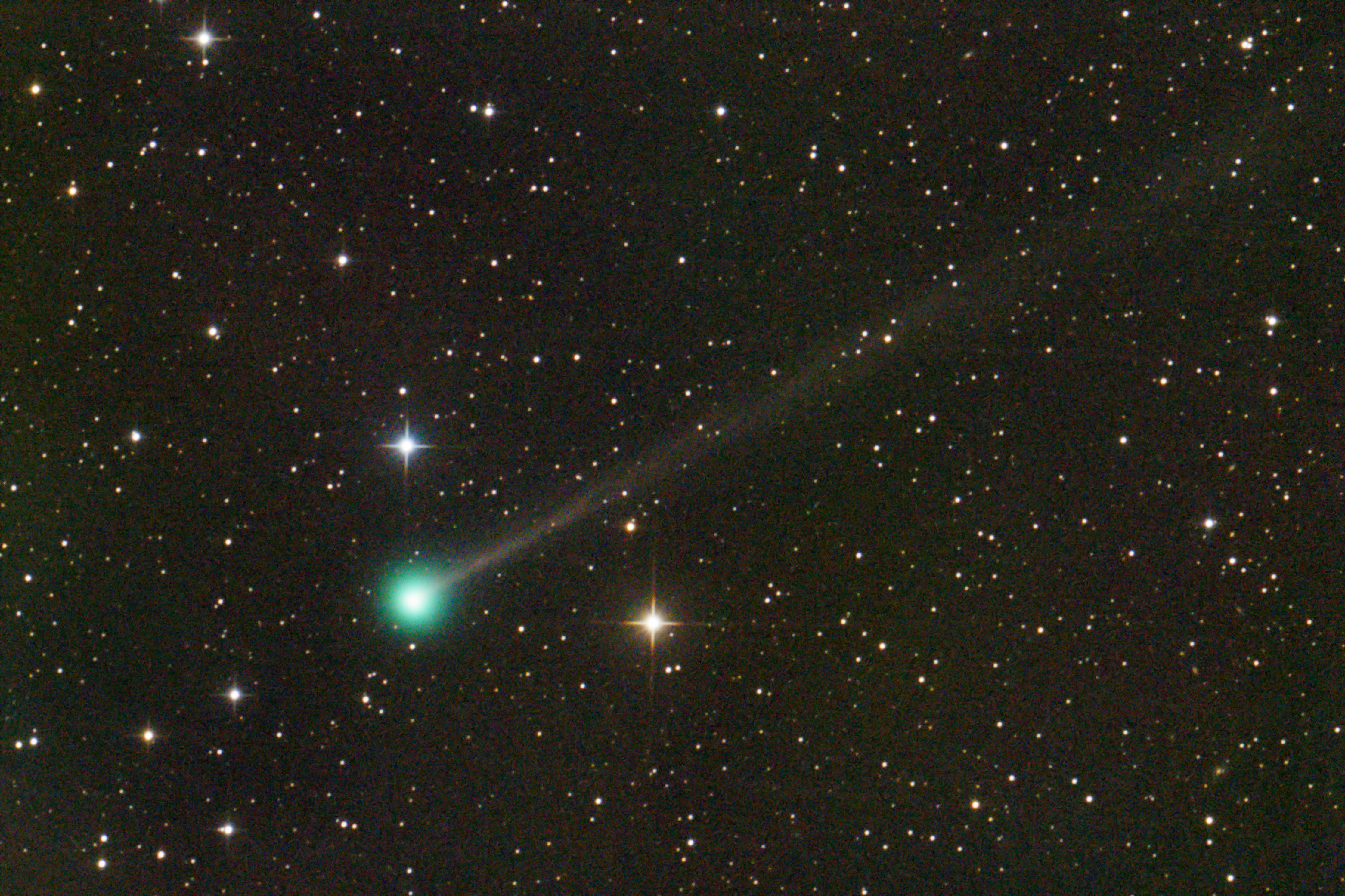 Starfield with bright comet in the centre, with a bright green head and a more faded tail.