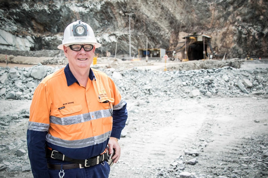 A male worker standing in open pit mine wearing hard hat