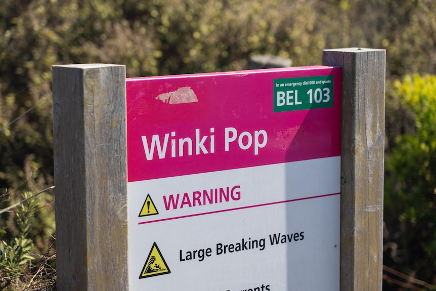 A sign at Winki Pop Beach that reads warning large breaking waves.