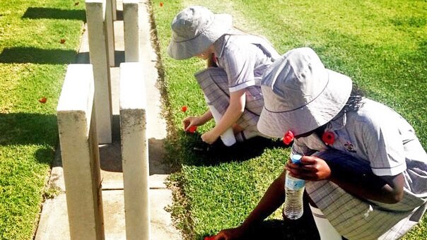 Two girls put poppies on graves at West Terrace Cemetery in Adelaide for Remembrance Day.