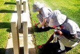 Two girls put poppies on graves at West Terrace Cemetery in Adelaide for Remembrance Day.