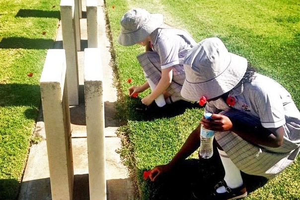 Two girls put poppies on graves at West Terrace Cemetery in Adelaide for Remembrance Day.