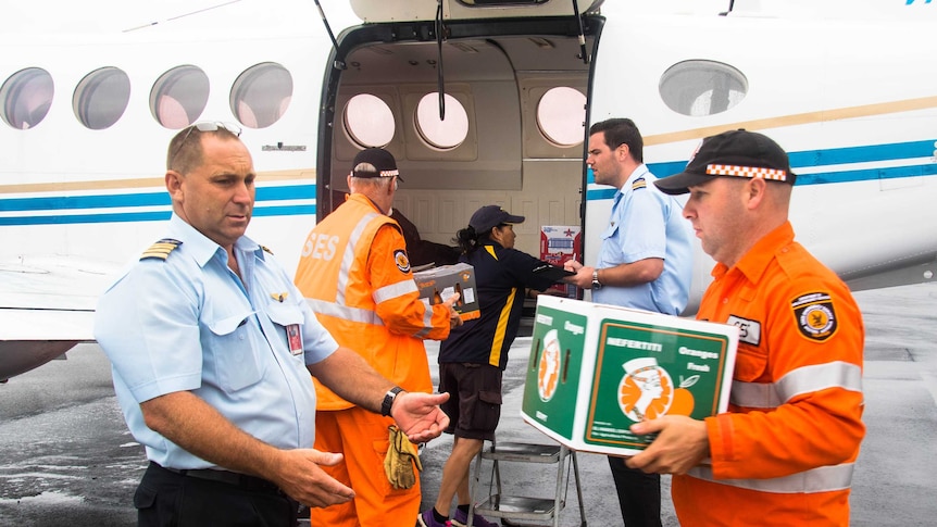 Emergency services officers and pilots load a plane with food.