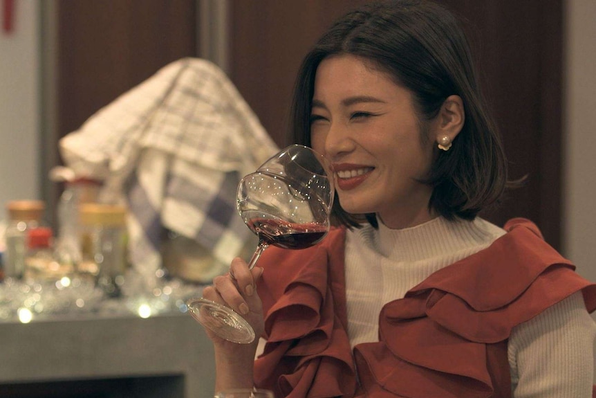 A young Japanese woman drinking a glass on red wine in the TV series Terrace House