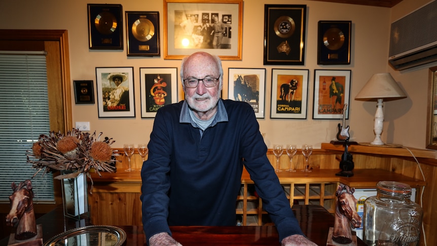 Athol Guy at home behind the bar with his awards behind him on the wall.