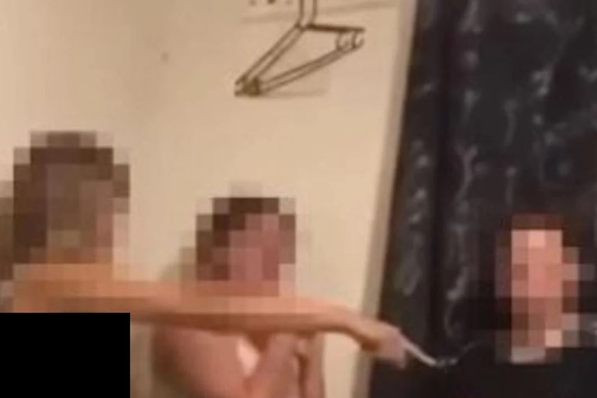 A blurred image of of three teen girls' heads and shoulders in a room with coathangers above one of the girls' heads.