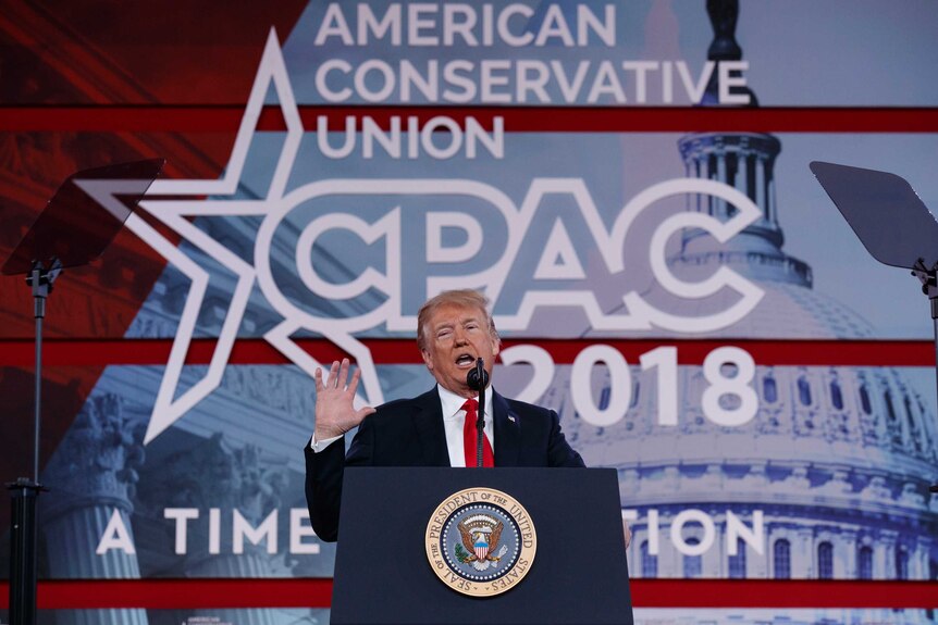 Donald Trump speaks at CPAC with his hand raised