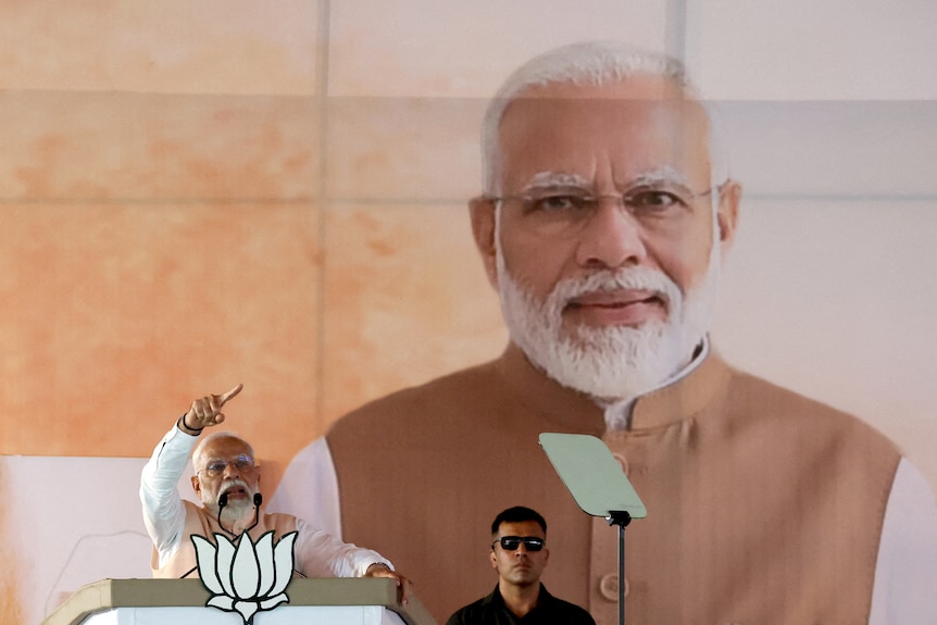 India's Prime Minister Narendra Modi speaks during an election campaign rally, next to a huge picture of his own head.