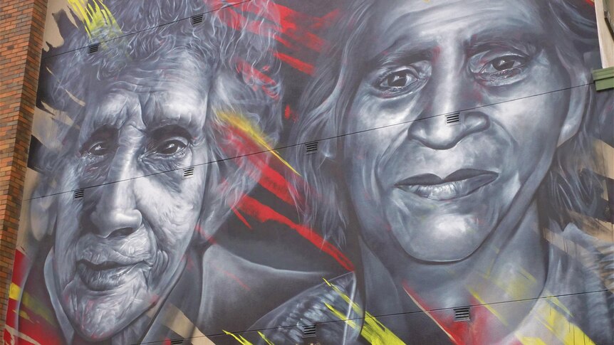 A close up of the two Yorta Yorta women's faces in the mural, painted in grey-scale, gently smiling. 