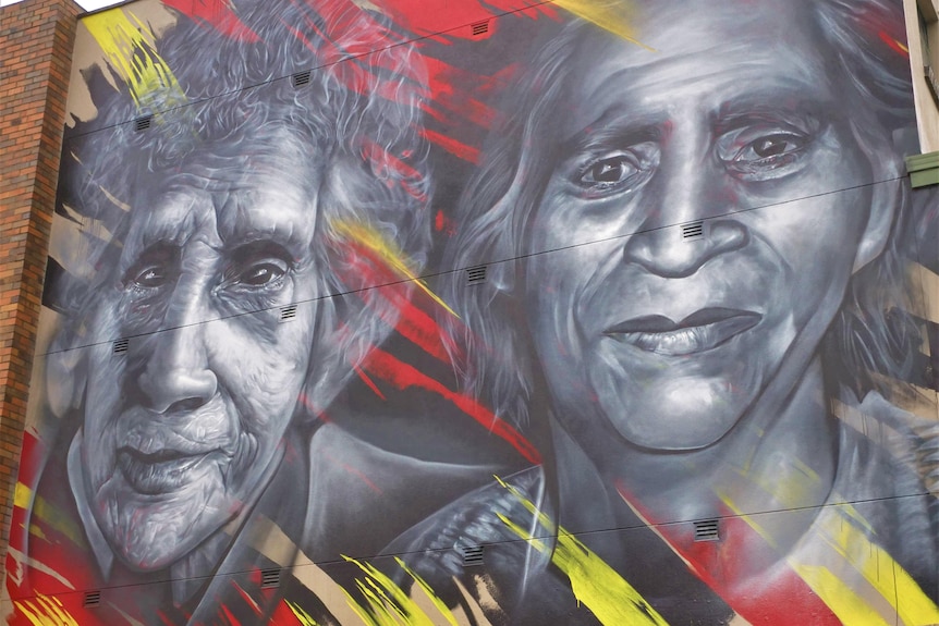 A close up of the two Yorta Yorta women's faces in the mural, painted in grey-scale, gently smiling. 