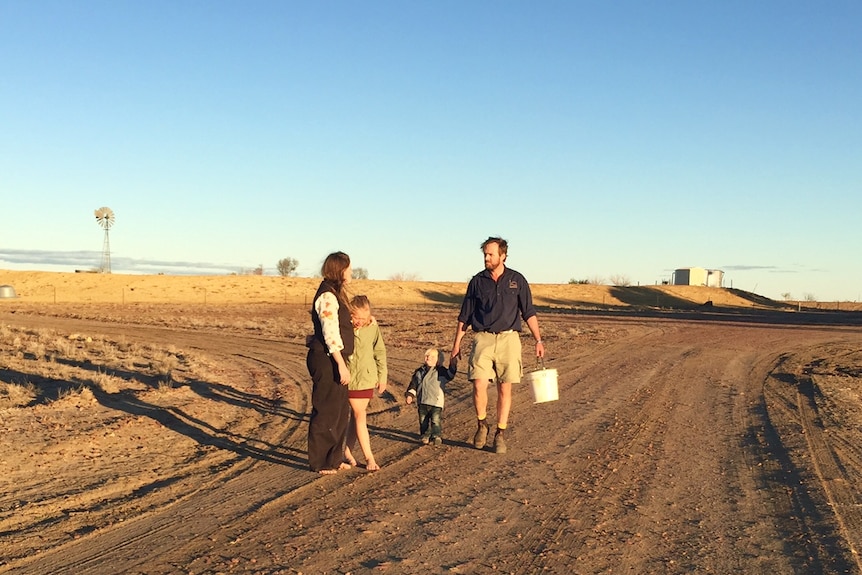 Carley and Nic Walker walking down a dirt road on their drought-affected sheep property.