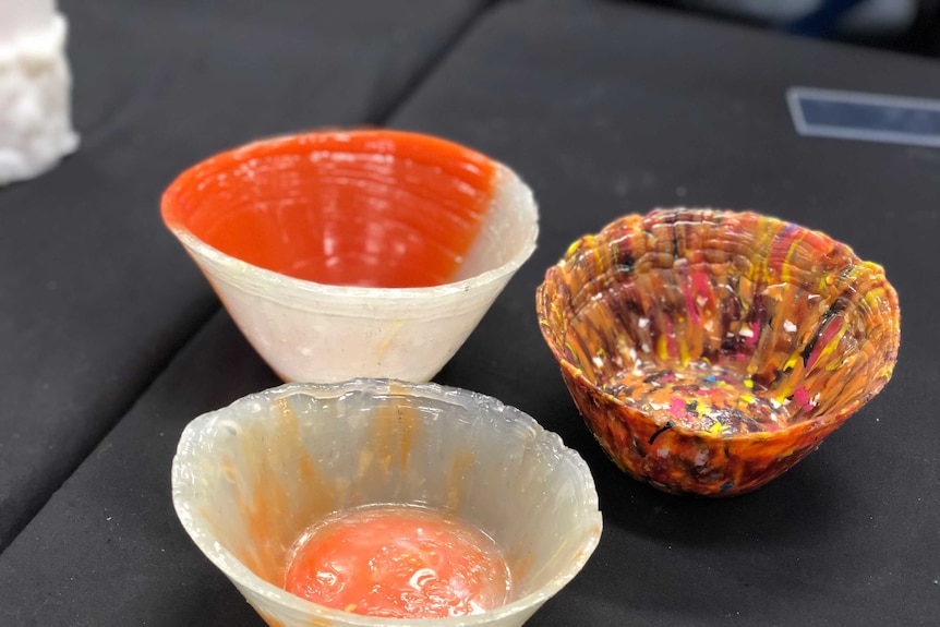 Three small and colourful bowls made by a machine that converts plastic waste into useful objects.