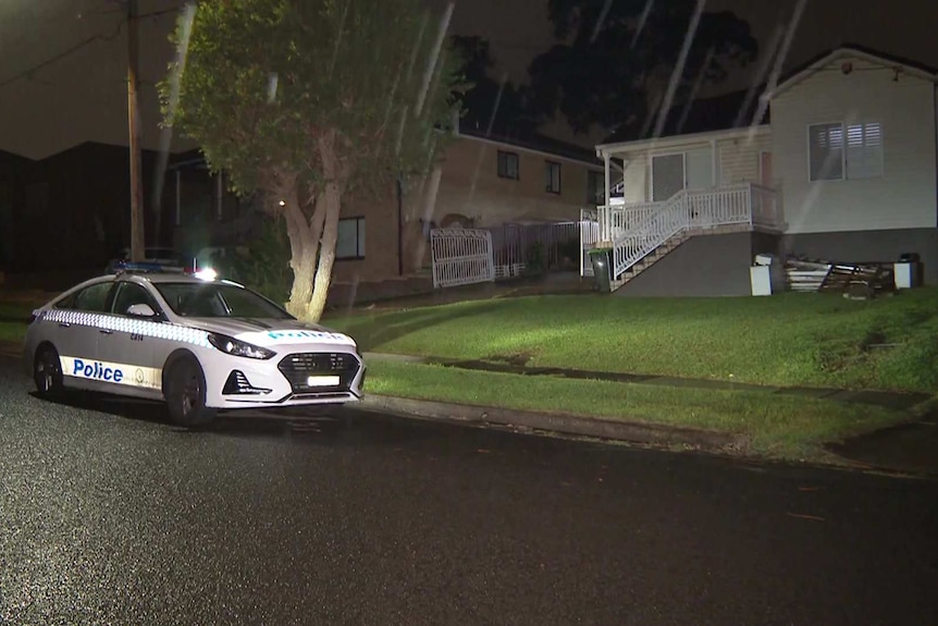 police car outside suburban home at night in rain