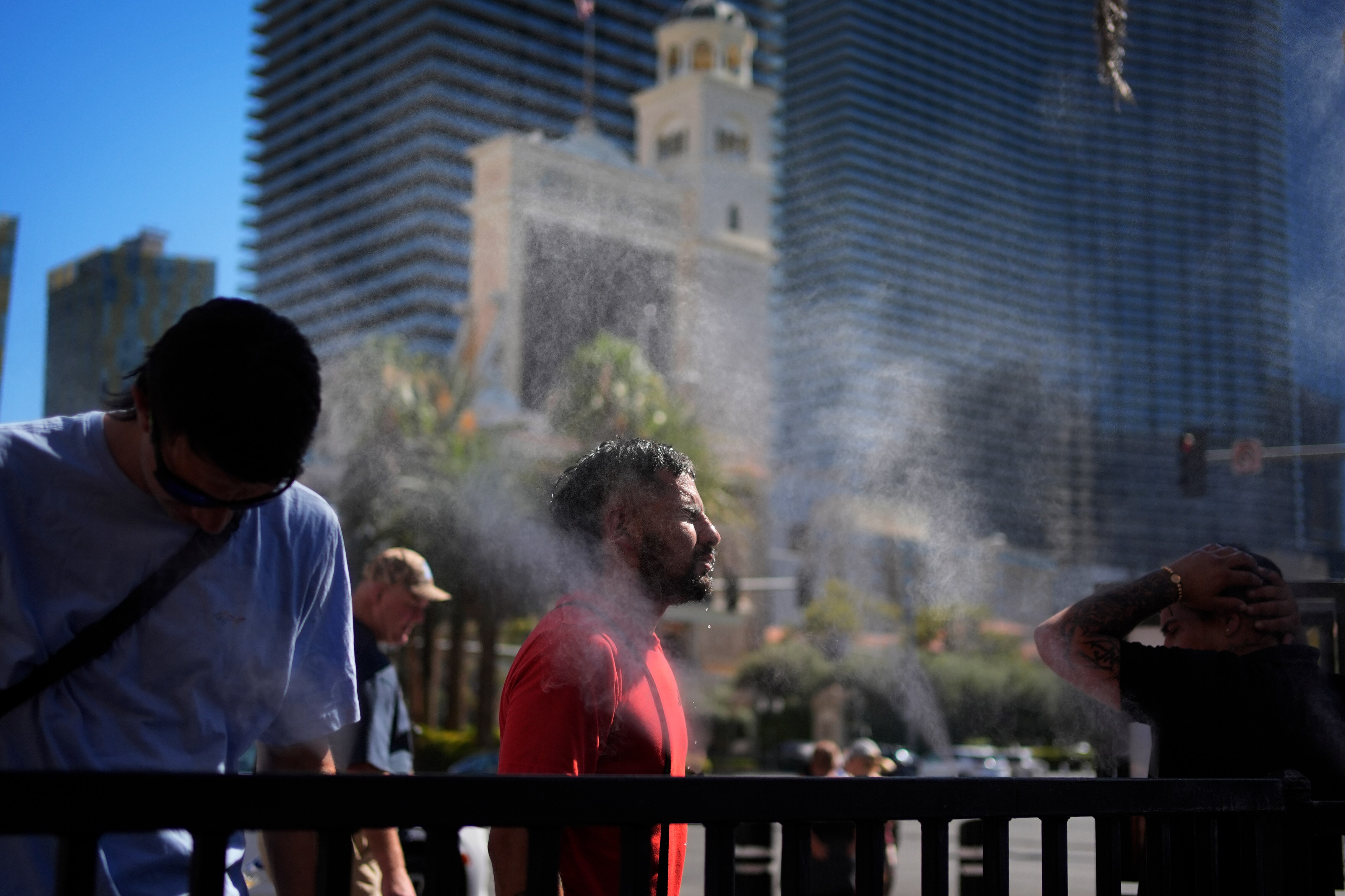 Four people stand in a sheet of mist on a street.