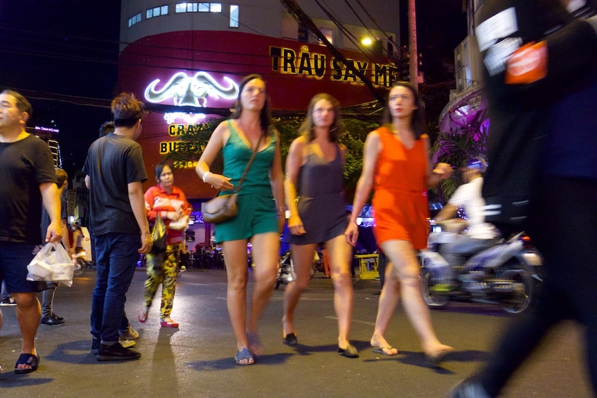 Western tourists walk along a busy tourist strip in Vietnam